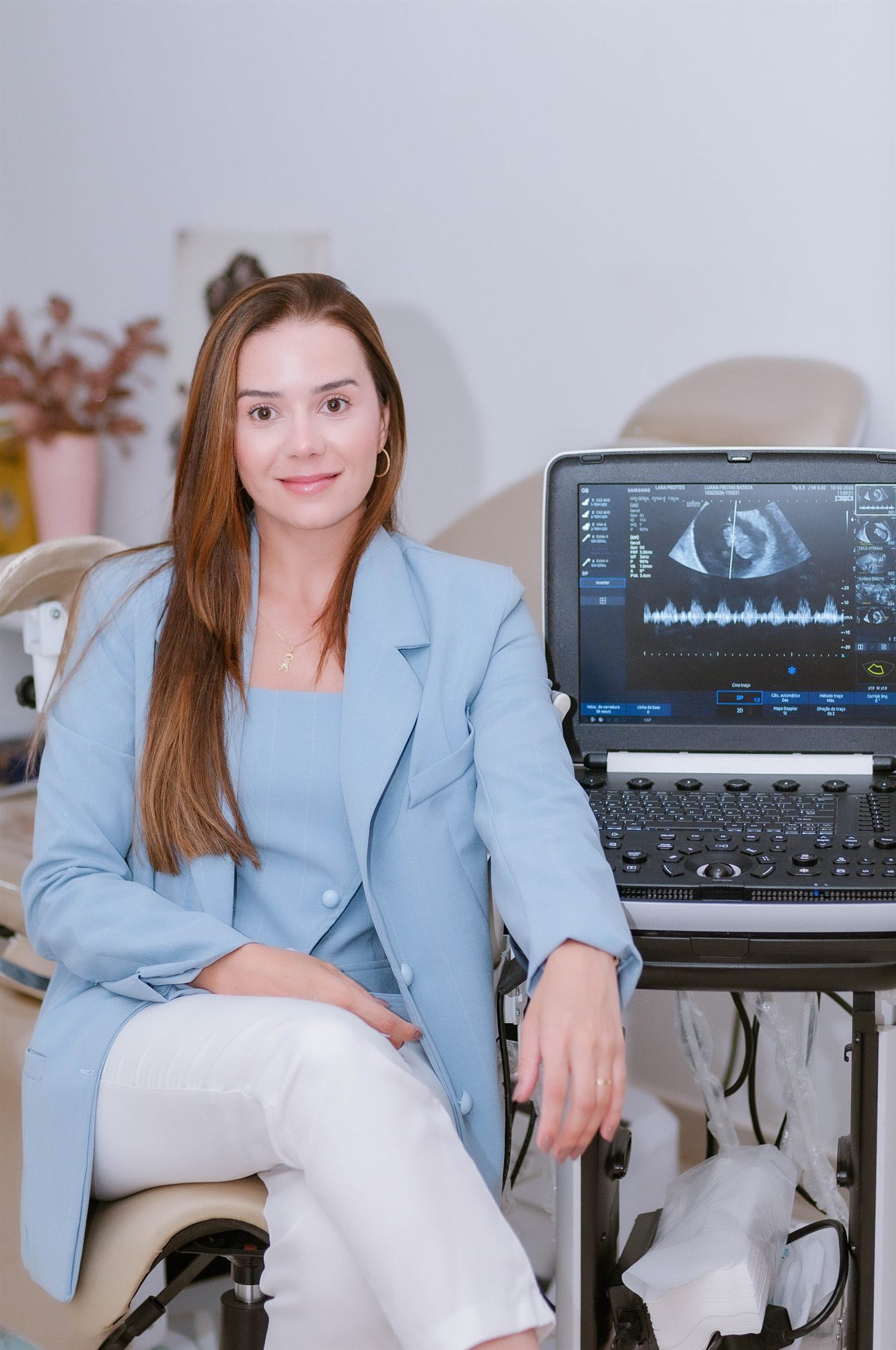 Dra. Lara Prottes ao lado do aparelho de ultrassom em seu consultório